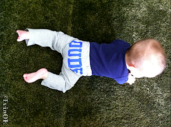 Baby crawling on green shag carpet with word DUDE across bum.
