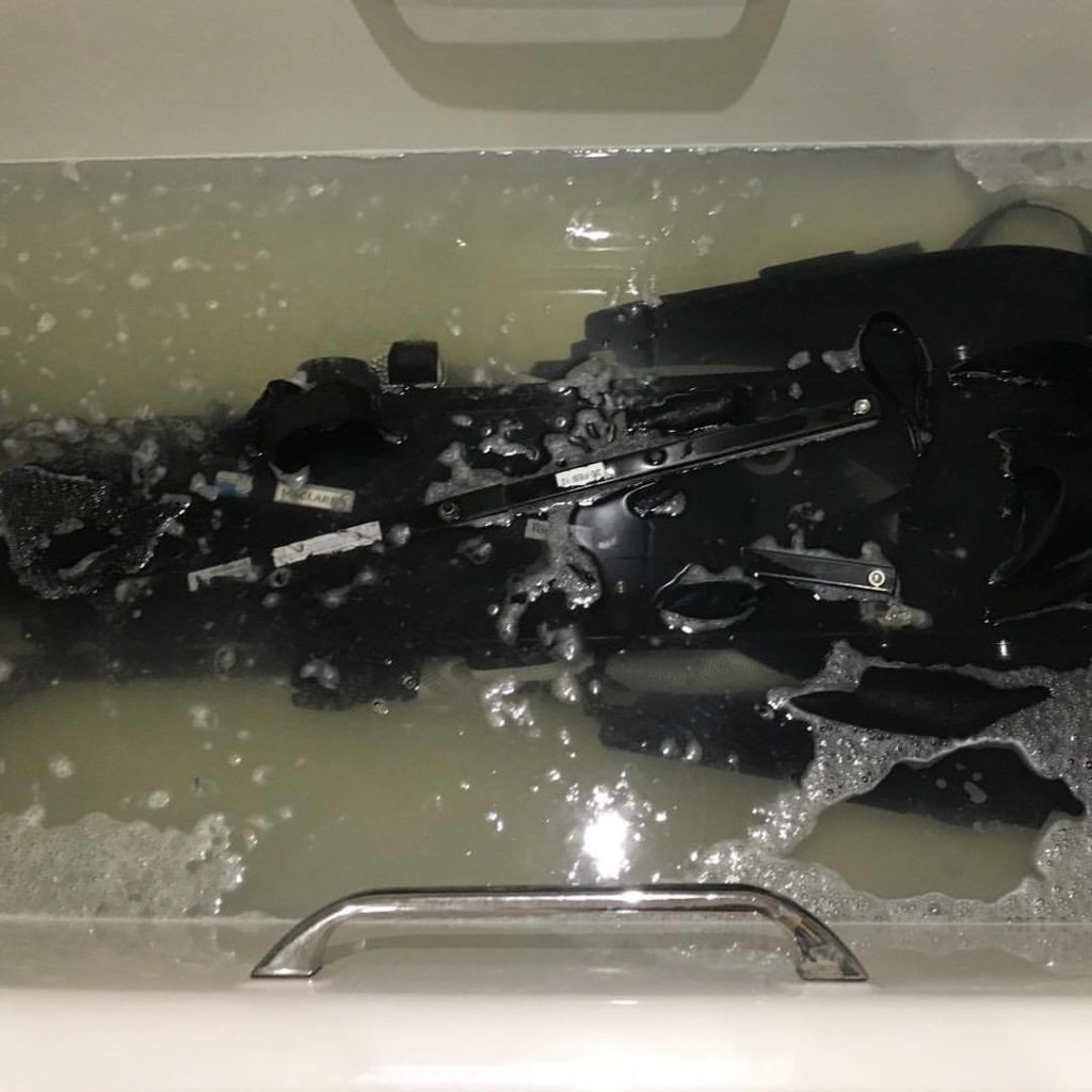 A dirty stroller in a bathtub getting clean