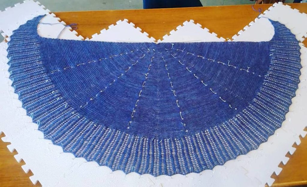 Falling Petals Shawl in Sweet Georgia CashLuxe rich Lupine blue on blocking boards at Stranded by the Sea