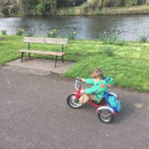 Schwinn Roadster Trike for Preschoolers rides by a little kid along a river