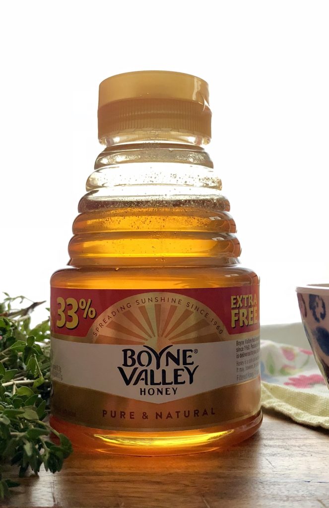 A back-lit bottle of Irish honey glowing like amber.