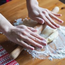 A pair of caucasian hands rolling dough to make a pie crust Photo by diliara garifullina