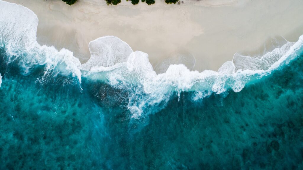 Waves against a beach shore from a drone above. Photo by Shifaaz Shamoon