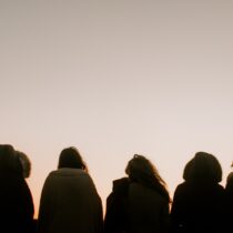Group of friends facing the sunset together.